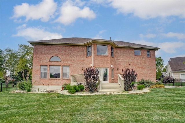 rear view of house with fence, a lawn, and brick siding