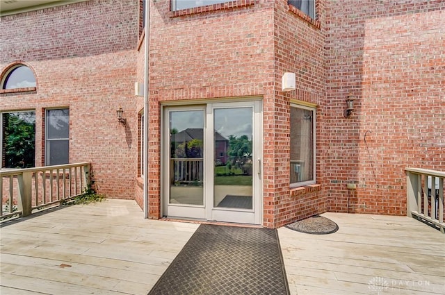 doorway to property with a deck and brick siding