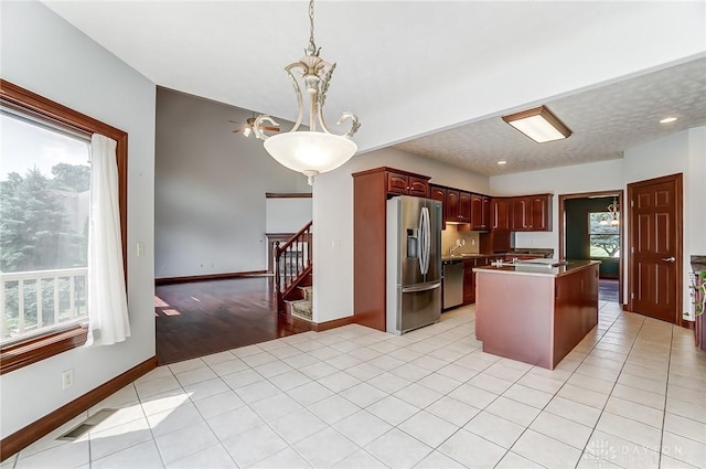 kitchen with a kitchen island, visible vents, appliances with stainless steel finishes, a wealth of natural light, and dark countertops