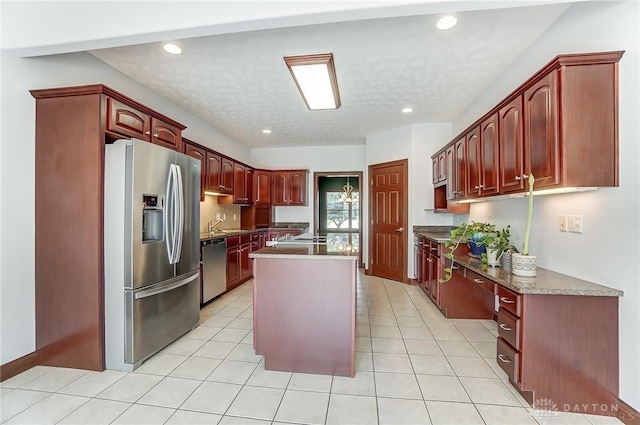 kitchen with recessed lighting, appliances with stainless steel finishes, light tile patterned flooring, a kitchen island, and dark brown cabinets