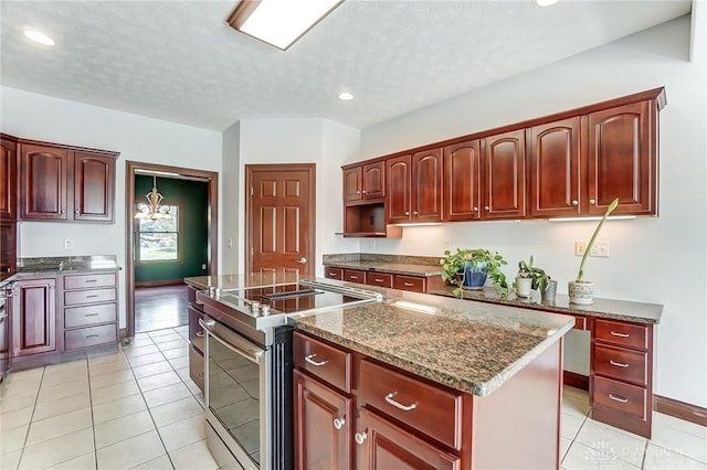 kitchen with stainless steel electric range oven, dark stone counters, light tile patterned flooring, and a kitchen island