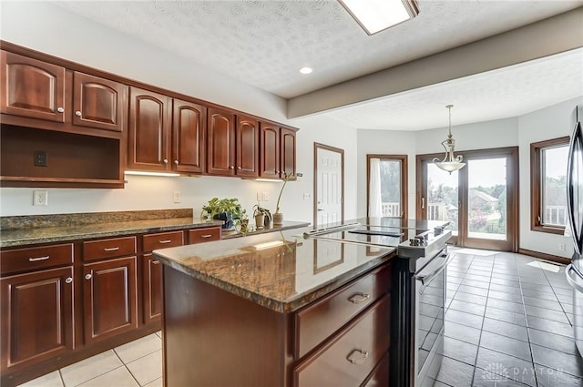 kitchen featuring a center island with sink, dark stone countertops, decorative light fixtures, stainless steel electric range, and a textured ceiling