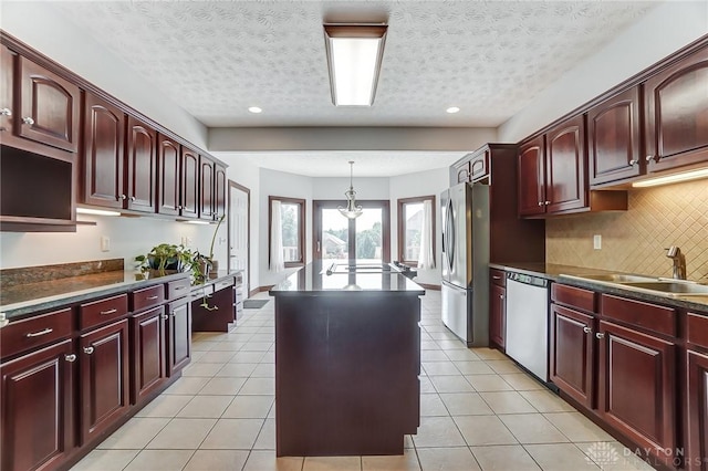 kitchen featuring light tile patterned floors, appliances with stainless steel finishes, decorative light fixtures, and a center island