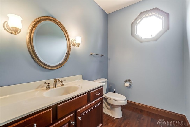 half bathroom featuring vanity, wood finished floors, and toilet