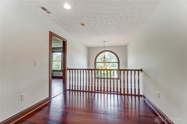 interior space featuring dark wood-style floors, a textured ceiling, plenty of natural light, and baseboards