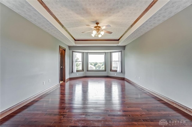 spare room featuring dark wood-style floors, ornamental molding, a raised ceiling, and a textured ceiling