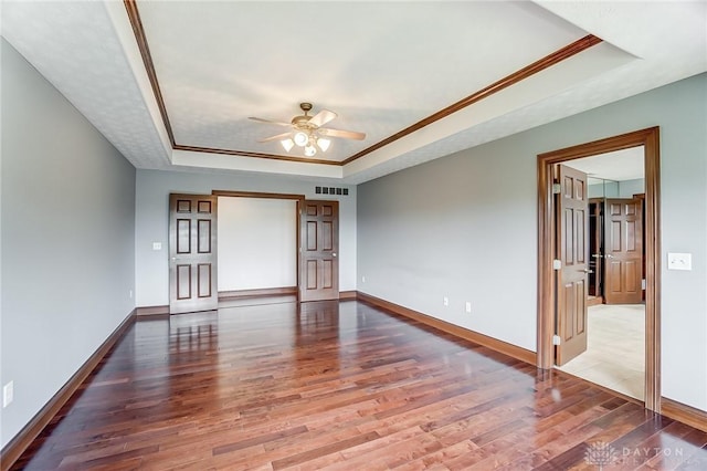 spare room featuring baseboards, visible vents, a raised ceiling, and wood finished floors