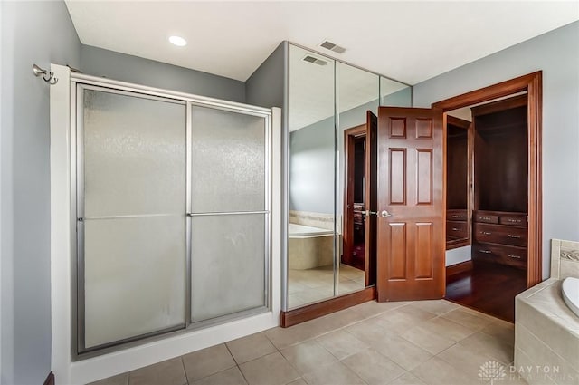 bathroom featuring a garden tub, a shower stall, and tile patterned floors