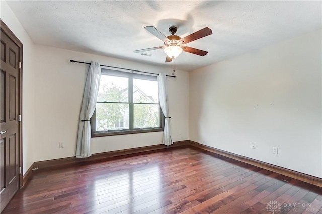 spare room featuring a ceiling fan, a textured ceiling, visible vents, and dark wood-type flooring