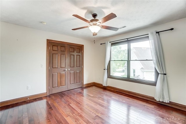 unfurnished bedroom with a closet, visible vents, baseboards, and wood finished floors