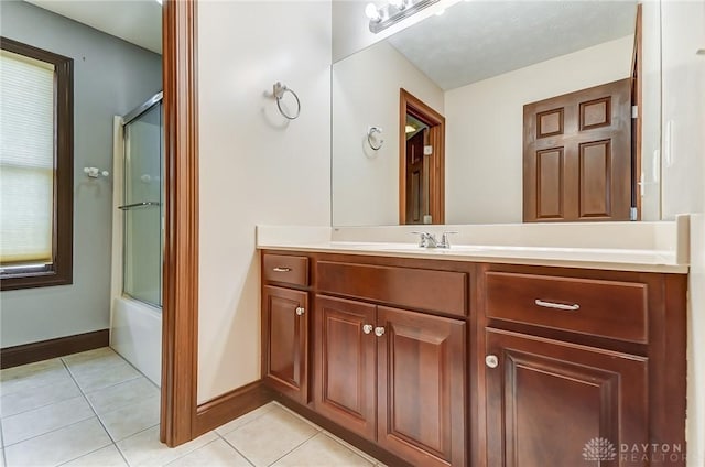 bathroom featuring shower / bath combination with glass door, tile patterned flooring, vanity, and baseboards