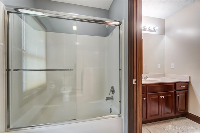 bathroom with tile patterned flooring, vanity, and bath / shower combo with glass door