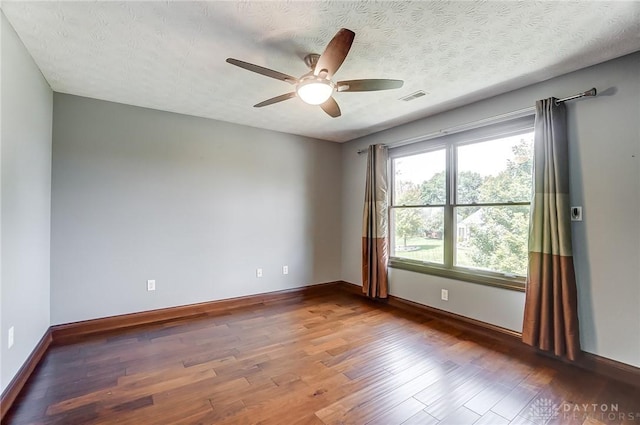 unfurnished room featuring a textured ceiling, ceiling fan, wood finished floors, visible vents, and baseboards