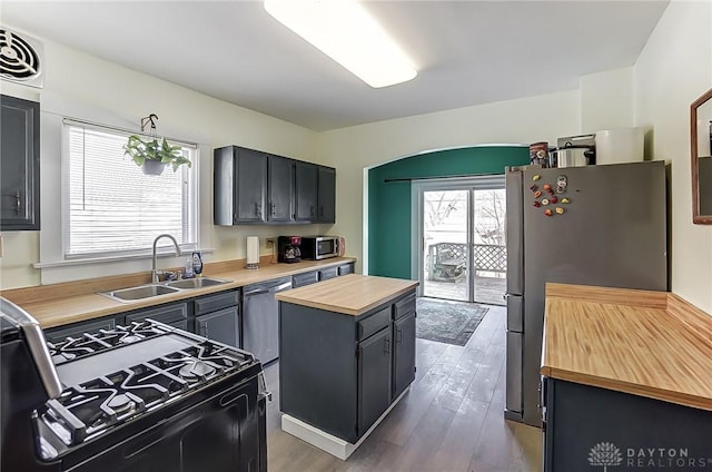 kitchen featuring appliances with stainless steel finishes, hardwood / wood-style floors, wood counters, sink, and a center island