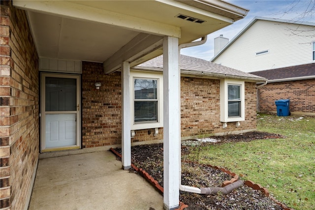 view of exterior entry with a patio and a yard