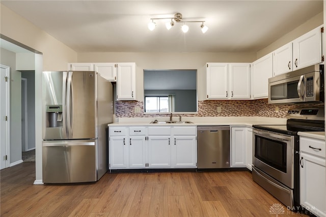 kitchen featuring sink, white cabinetry, light hardwood / wood-style flooring, appliances with stainless steel finishes, and backsplash