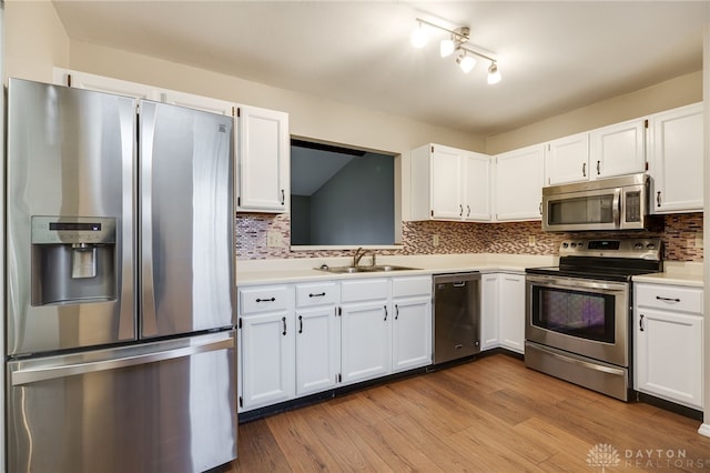 kitchen featuring sink, appliances with stainless steel finishes, white cabinetry, backsplash, and light wood-type flooring