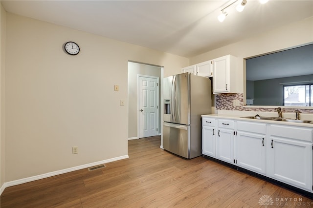 kitchen with white cabinetry, stainless steel fridge, sink, and backsplash