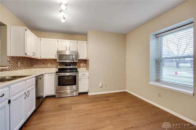 kitchen featuring sink, white cabinetry, stainless steel appliances, light hardwood / wood-style floors, and decorative backsplash