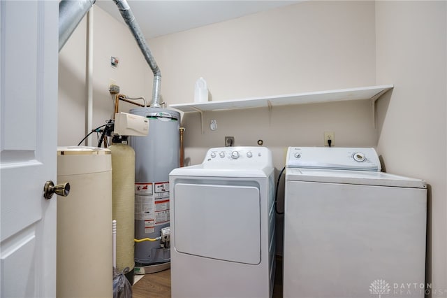 clothes washing area with hardwood / wood-style floors, water heater, and washing machine and clothes dryer