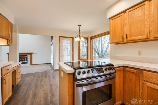 kitchen with dark hardwood / wood-style floors, a notable chandelier, decorative light fixtures, stainless steel range with electric cooktop, and kitchen peninsula