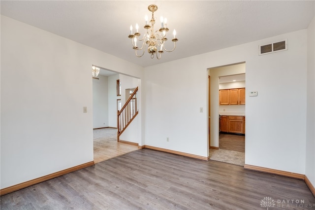 empty room featuring a chandelier and light wood-type flooring