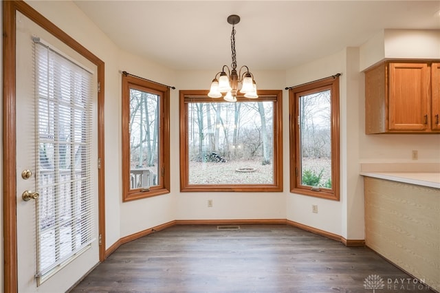 unfurnished dining area with dark hardwood / wood-style flooring and a notable chandelier