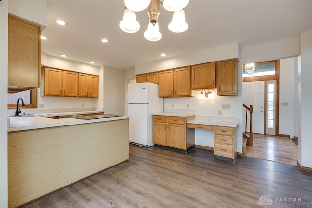 kitchen featuring wood-type flooring, white fridge, sink, and a notable chandelier