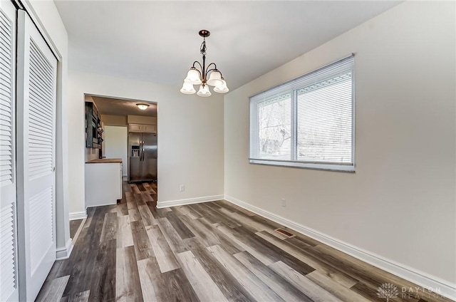 unfurnished dining area with hardwood / wood-style floors and a notable chandelier