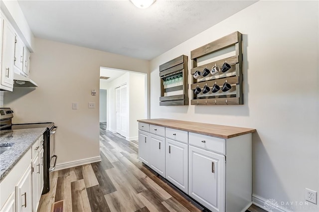 kitchen featuring white cabinetry, butcher block countertops, electric range, and light hardwood / wood-style floors