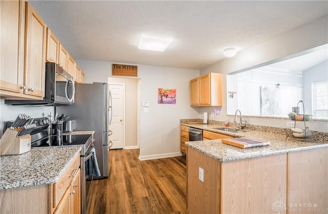 kitchen with appliances with stainless steel finishes, sink, light stone counters, kitchen peninsula, and light brown cabinets