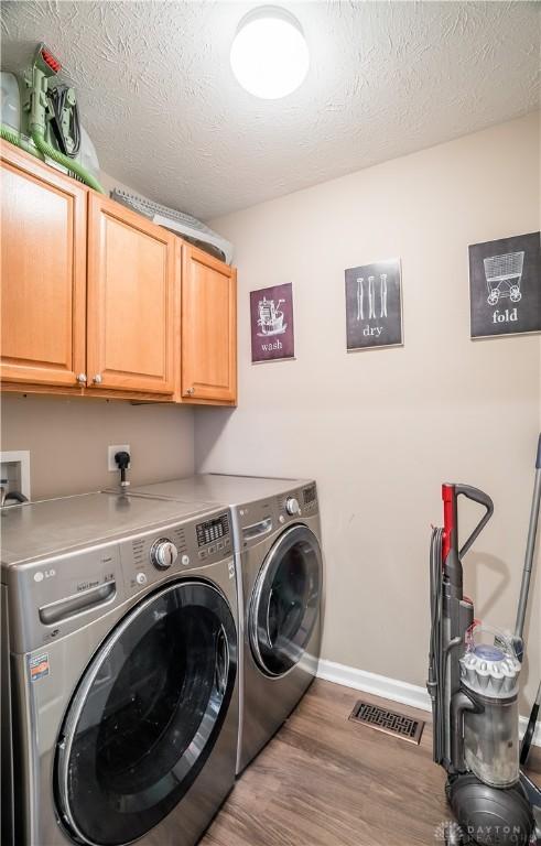 laundry room with cabinets, separate washer and dryer, hardwood / wood-style floors, and a textured ceiling