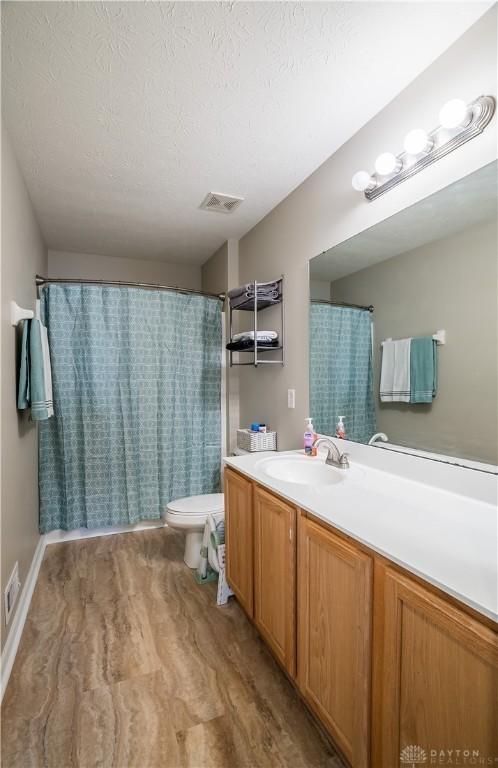 bathroom featuring vanity, a textured ceiling, wood-type flooring, and toilet