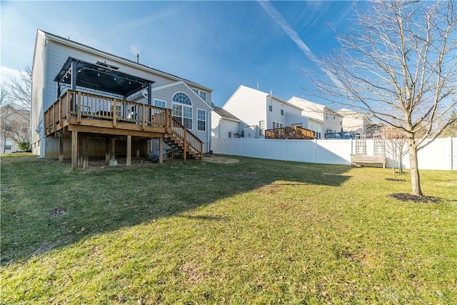 rear view of property featuring a wooden deck and a lawn