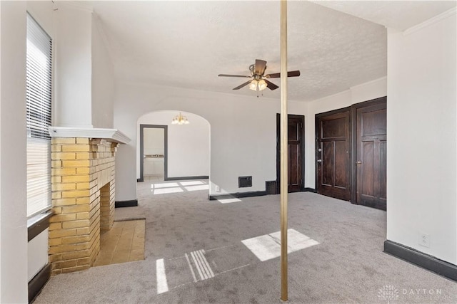 unfurnished living room featuring ceiling fan, light carpet, a brick fireplace, and a textured ceiling