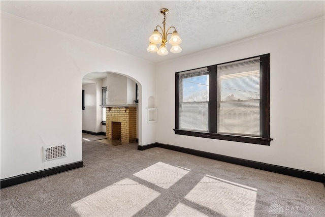 carpeted spare room with a notable chandelier, crown molding, and a textured ceiling