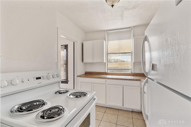 kitchen with a textured ceiling, light tile patterned floors, white cabinets, and white appliances