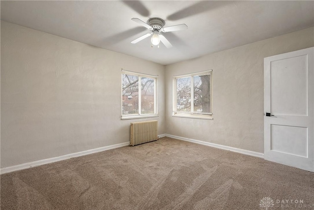 carpeted spare room featuring radiator and ceiling fan