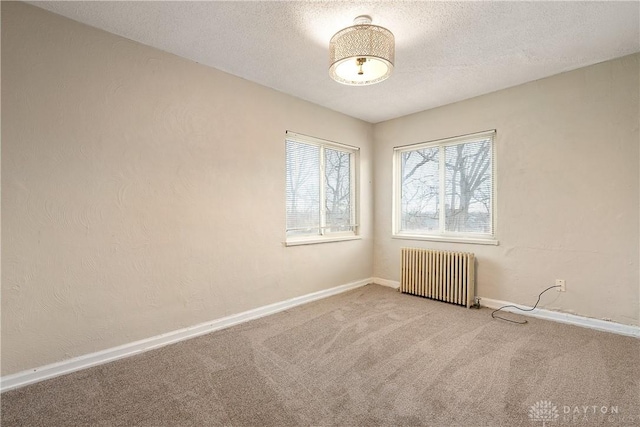 unfurnished room featuring carpet flooring, radiator heating unit, and a textured ceiling