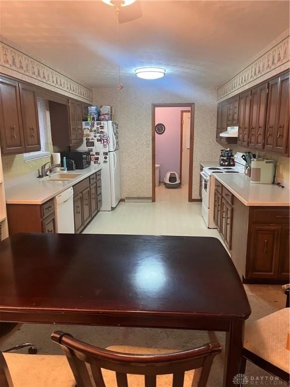 kitchen with white appliances, light floors, light countertops, under cabinet range hood, and a sink