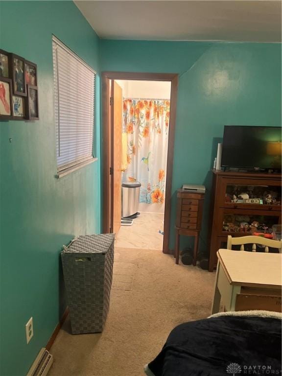 bedroom with a baseboard radiator, light colored carpet, and ensuite bathroom