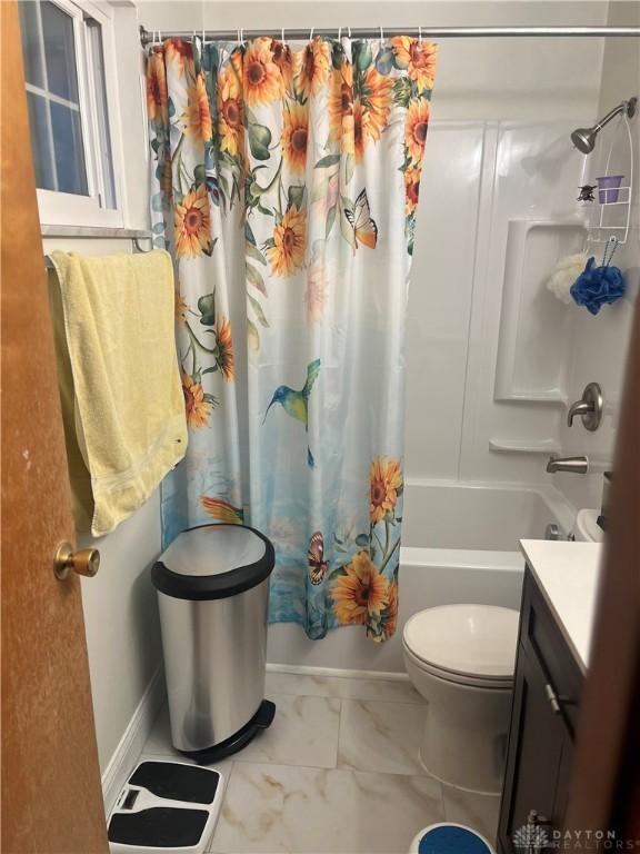 bathroom featuring toilet, marble finish floor, shower / bath combo, and vanity