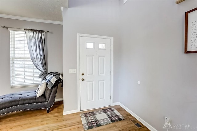 entrance foyer with hardwood / wood-style flooring, crown molding, and a textured ceiling