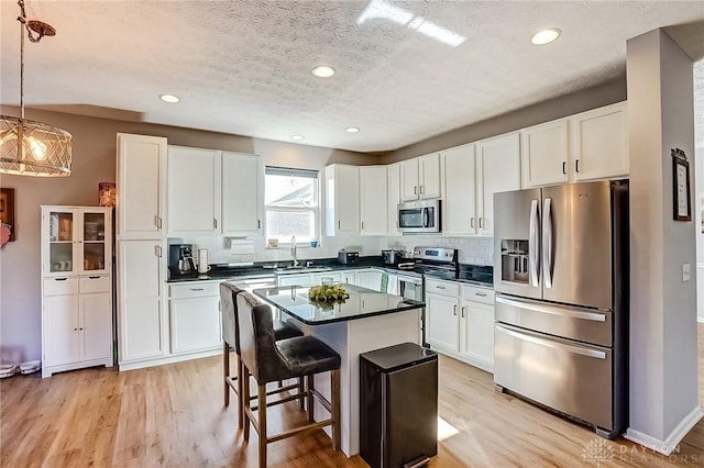 kitchen with a kitchen island, decorative light fixtures, white cabinetry, a kitchen breakfast bar, and stainless steel appliances