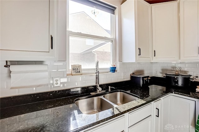 kitchen featuring dark stone countertops, sink, decorative backsplash, and white cabinets