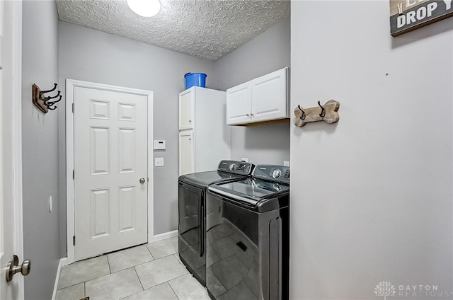 washroom featuring separate washer and dryer, light tile patterned floors, cabinets, and a textured ceiling