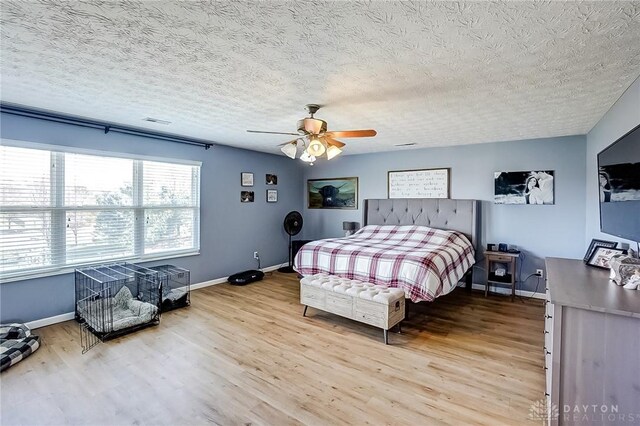 bedroom with hardwood / wood-style floors, a textured ceiling, and ceiling fan