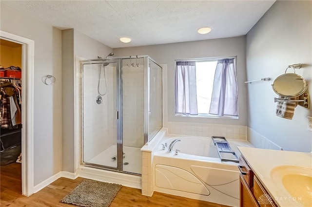 bathroom with hardwood / wood-style flooring, vanity, plus walk in shower, and a textured ceiling