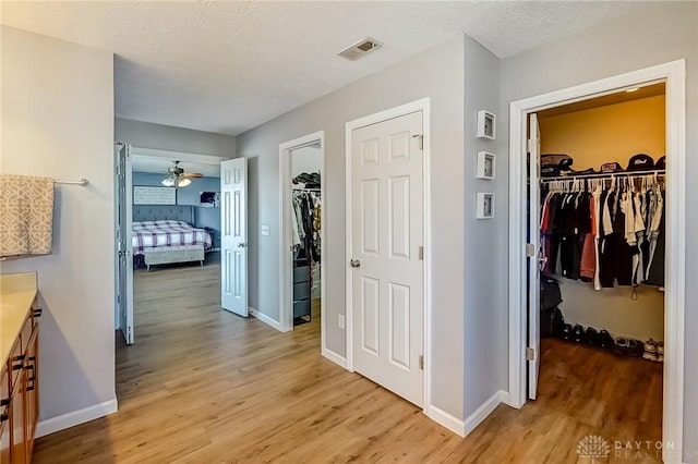 corridor with light hardwood / wood-style flooring and a textured ceiling