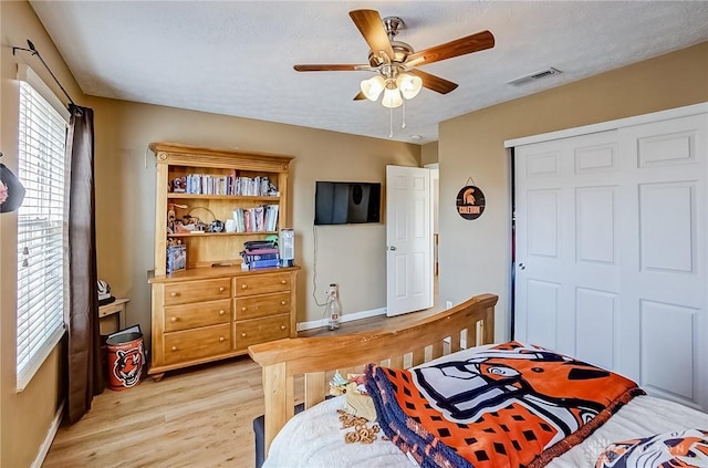 bedroom featuring ceiling fan, light hardwood / wood-style floors, and a closet